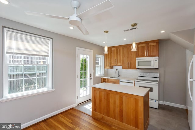 kitchen featuring a sink, white appliances, visible vents, baseboards, and light countertops