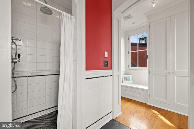 9425 Blackpond Ln, Delaplane, VA 20144 - bathroom featuring wood finished floors, a tile shower, wainscoting, and tile walls
