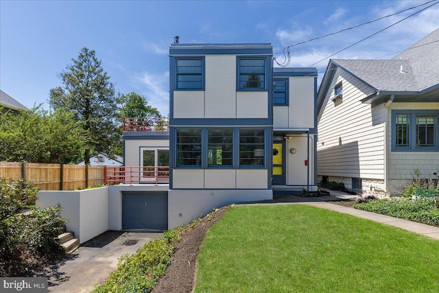 modern home featuring an attached garage, fence, a front yard, and concrete driveway