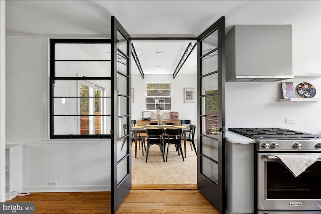 kitchen featuring baseboards, light countertops, light wood-style flooring, and stainless steel gas range oven