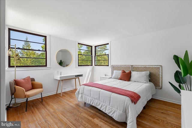 bedroom with baseboards, multiple windows, and wood finished floors