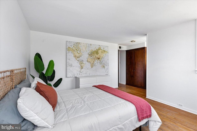 bedroom with baseboards, visible vents, and wood finished floors