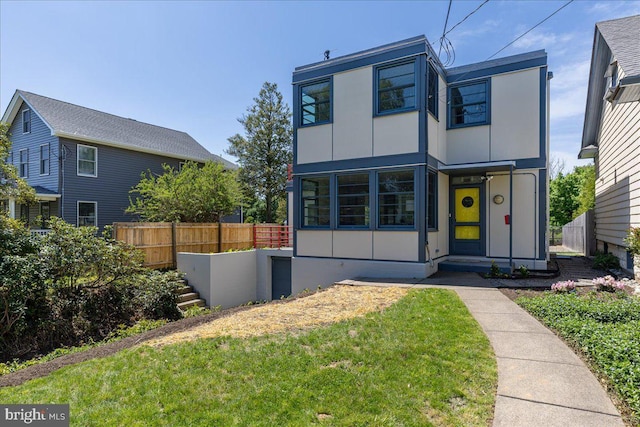 modern home featuring board and batten siding, fence, and a front yard