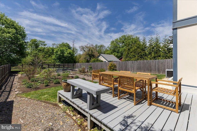 wooden deck featuring central air condition unit, outdoor dining area, and a fenced backyard