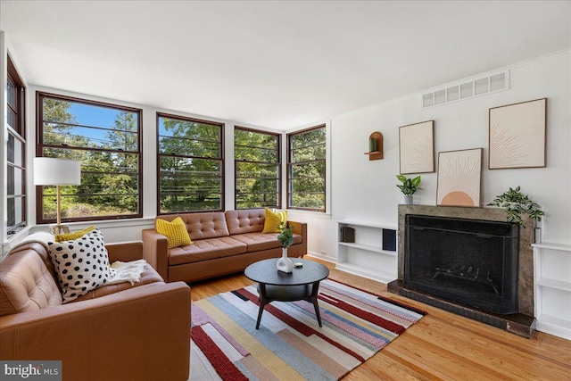 living room with plenty of natural light, a fireplace, wood finished floors, and visible vents