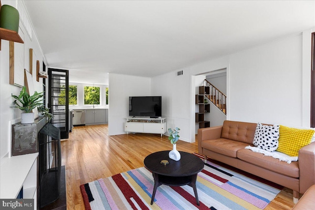 living room with visible vents, light wood-style flooring, and stairway