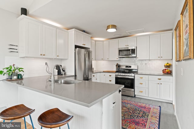 4600 Blagden Ter NW, Washington, DC 20011 - kitchen with stainless steel appliances, a sink, a peninsula, white cabinetry, and backsplash