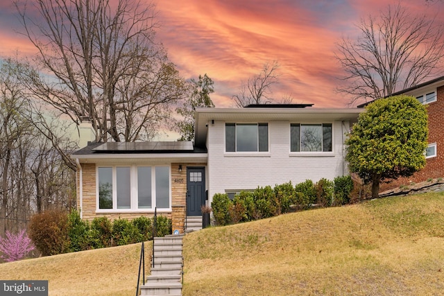 4600 Blagden Ter NW, Washington, DC 20011 - tri-level home with roof mounted solar panels, a front yard, stone siding, and brick siding