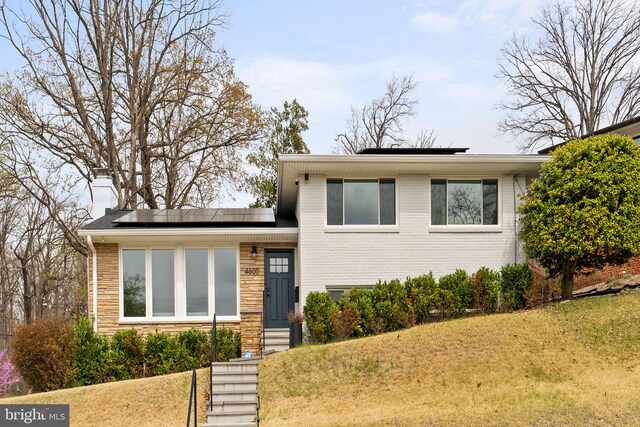 4600 Blagden Ter NW, Washington, DC 20011 - split level home featuring solar panels, a front yard, and stone siding