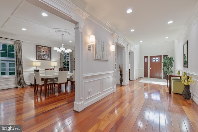 foyer entrance with a chandelier, a decorative wall, hardwood / wood-style floors, and crown molding