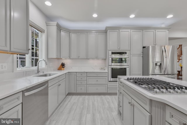 kitchen featuring recessed lighting, light stone countertops, a sink, and appliances with stainless steel finishes