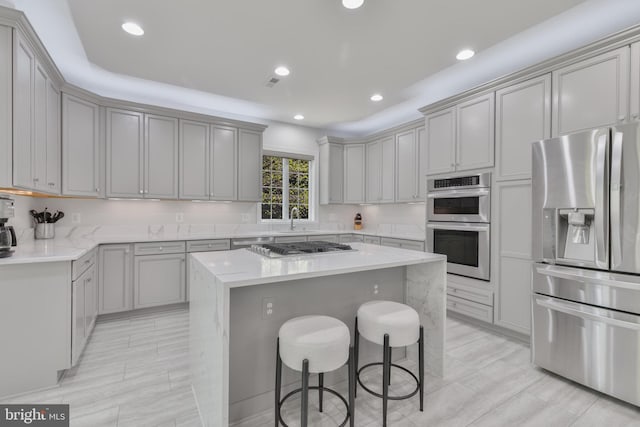 kitchen featuring a sink, appliances with stainless steel finishes, a kitchen breakfast bar, recessed lighting, and a kitchen island
