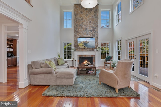 living area with a fireplace, visible vents, baseboards, and hardwood / wood-style floors