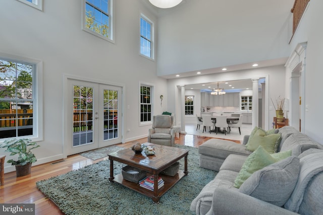 living room with baseboards, decorative columns, an inviting chandelier, and hardwood / wood-style flooring