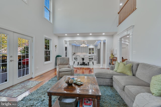 living room with a wealth of natural light, baseboards, an inviting chandelier, and wood finished floors