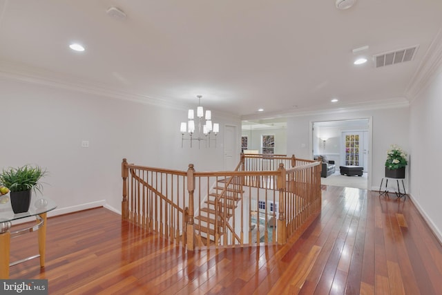 corridor with visible vents, a notable chandelier, ornamental molding, and an upstairs landing