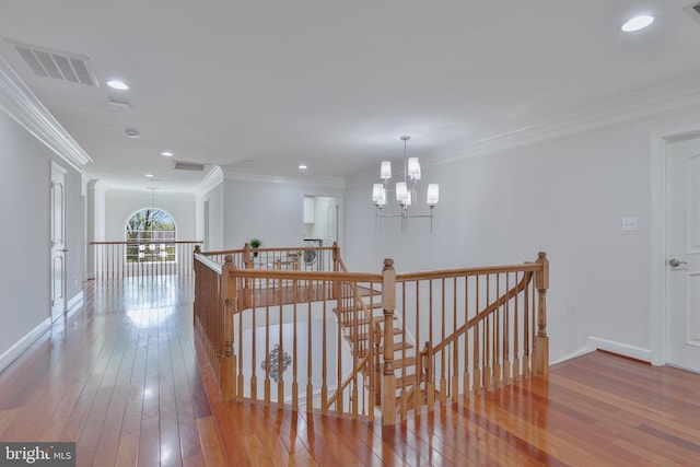 hall with a chandelier, an upstairs landing, ornamental molding, and visible vents