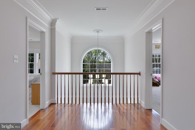 hall with crown molding, wood finished floors, baseboards, and visible vents