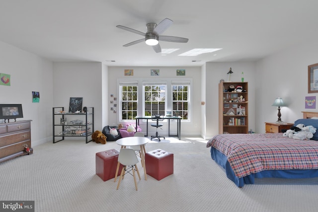 carpeted bedroom featuring baseboards, a ceiling fan, and a skylight