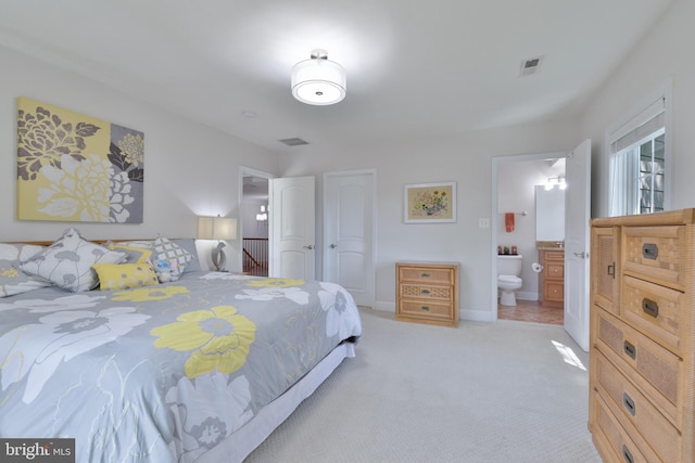bedroom featuring visible vents, baseboards, ensuite bath, and light carpet
