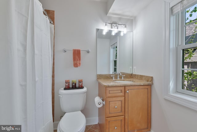 bathroom with a wealth of natural light, tile patterned floors, vanity, and toilet
