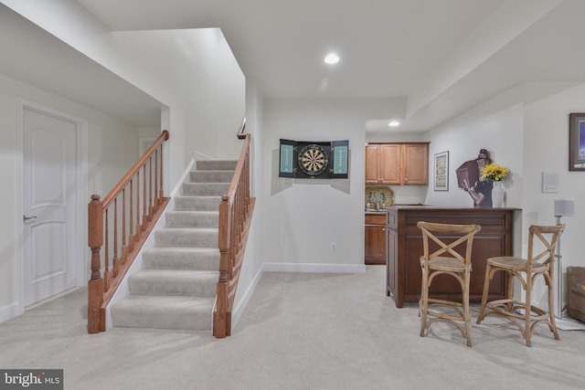 interior space featuring light colored carpet, recessed lighting, a bar, stairway, and baseboards