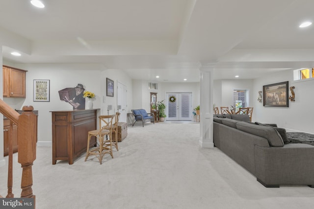 living area featuring a raised ceiling, ornate columns, light colored carpet, and recessed lighting