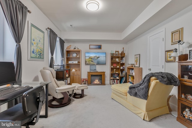 carpeted living area featuring a glass covered fireplace