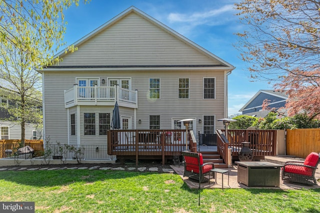 back of house with a lawn, an outdoor fire pit, a patio area, fence, and a balcony