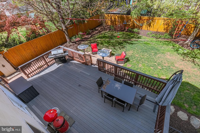 wooden terrace with area for grilling, a fenced backyard, outdoor dining area, and a lawn
