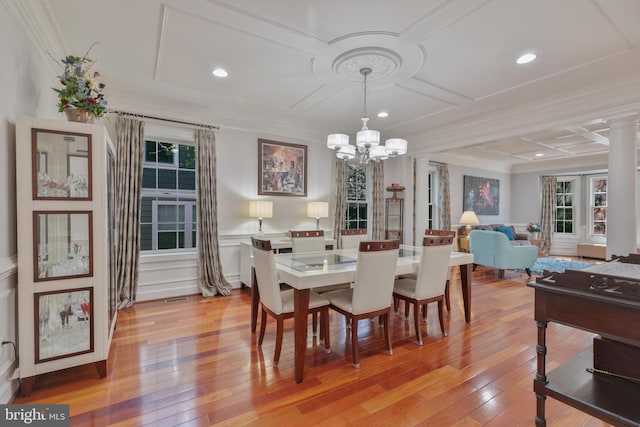 dining room featuring coffered ceiling, light wood-type flooring, an inviting chandelier, and ornamental molding