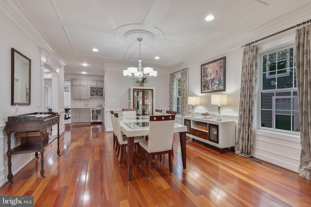 dining space featuring ornamental molding, a chandelier, wine cooler, recessed lighting, and hardwood / wood-style floors