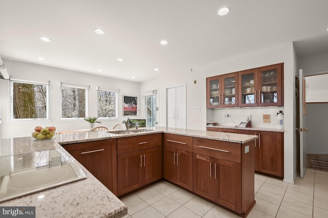 kitchen with light stone countertops, glass insert cabinets, white electric cooktop, and light tile patterned floors