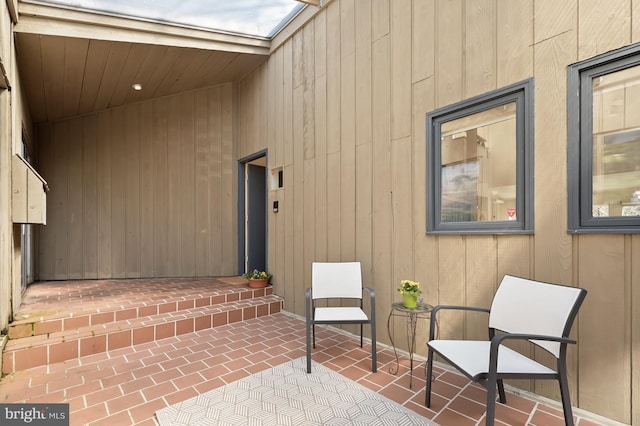 exterior space with wood walls and brick floor