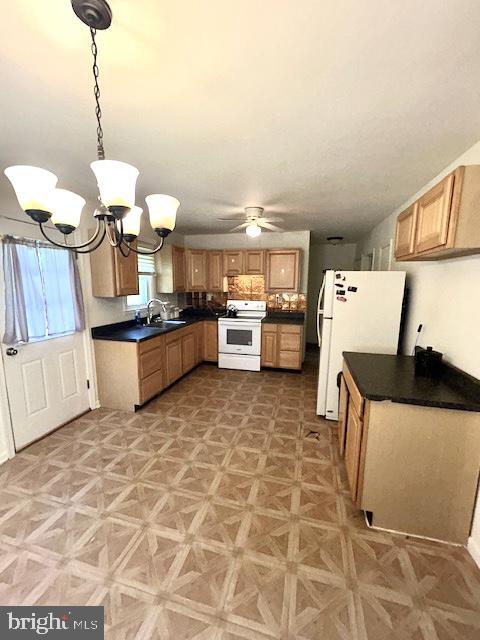 136 Charles Pl, Indian Head, MD 20640 - kitchen with a sink, white appliances, dark countertops, hanging light fixtures, and ceiling fan with notable chandelier