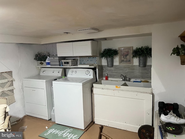 clothes washing area featuring cabinet space, separate washer and dryer, and a sink