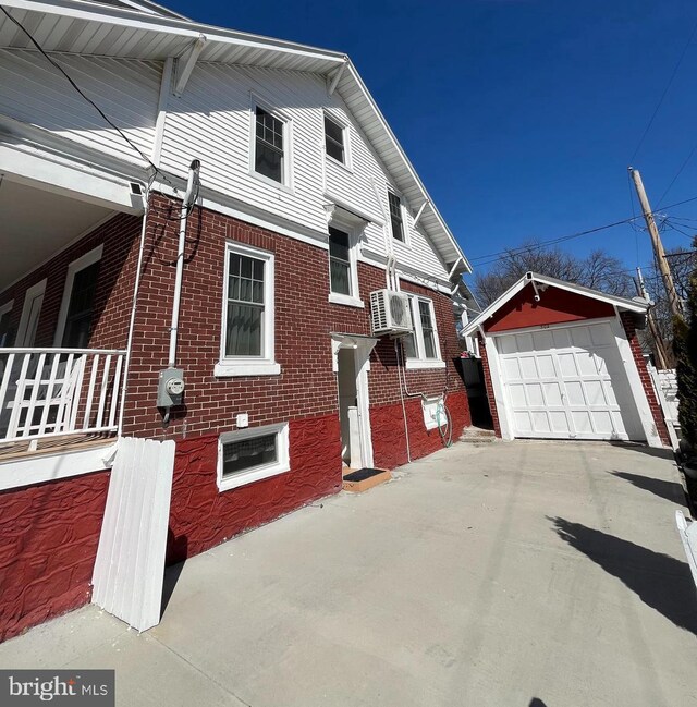 view of side of property with a garage, brick siding, an outdoor structure, and concrete driveway