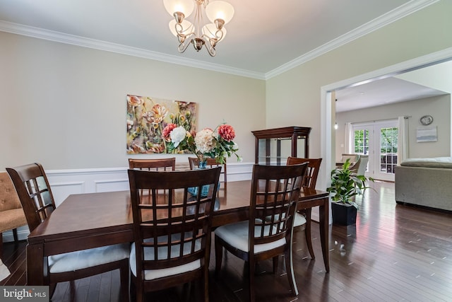 dining area with ornamental molding, wainscoting, hardwood / wood-style flooring, and a notable chandelier