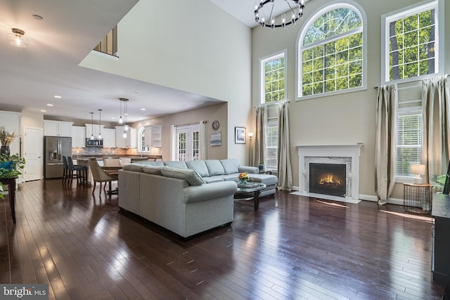 living area featuring plenty of natural light, a fireplace, dark wood finished floors, and a towering ceiling