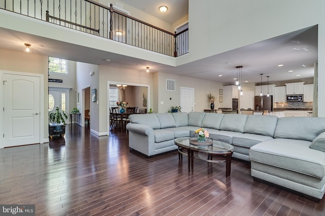 living room with visible vents, baseboards, a high ceiling, dark wood-style floors, and recessed lighting