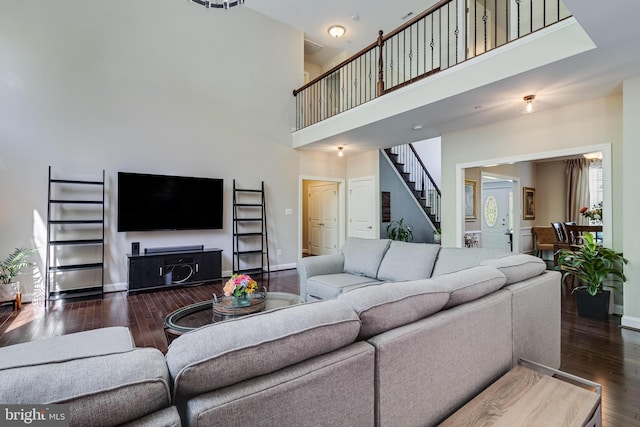 living area featuring baseboards, a high ceiling, hardwood / wood-style flooring, and stairway