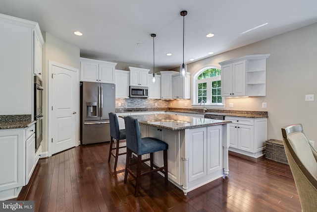 kitchen featuring dark wood-style flooring, appliances with stainless steel finishes, a kitchen island, and white cabinets