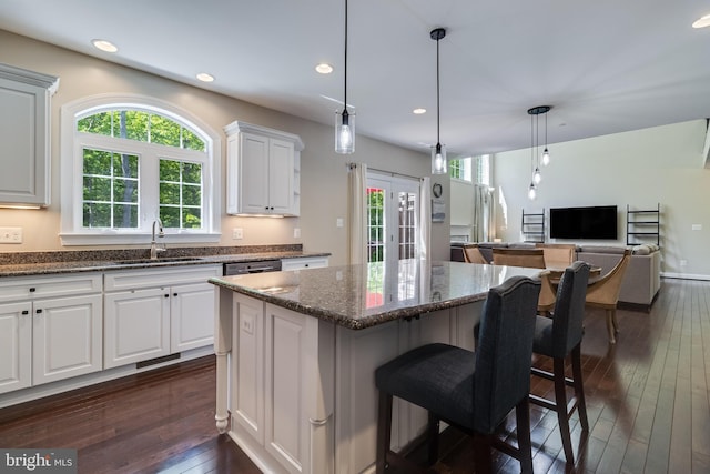 kitchen featuring plenty of natural light, a sink, dark wood-style flooring, and a center island