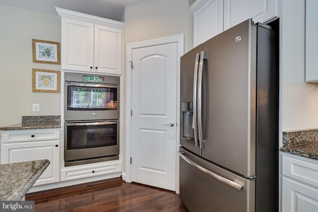 kitchen featuring dark stone counters, dark wood-style flooring, appliances with stainless steel finishes, and white cabinets
