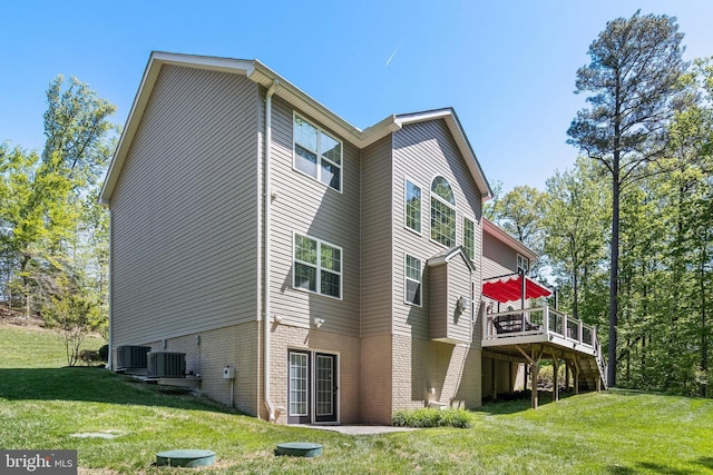 back of property with a lawn, brick siding, a wooden deck, and central AC unit