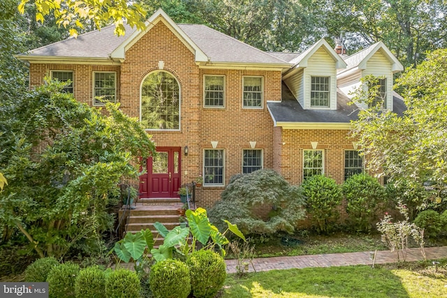 view of front of property with a shingled roof and brick siding