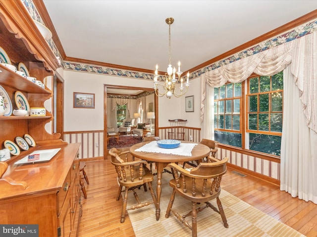 dining room with light wood finished floors, crown molding, a chandelier, and visible vents