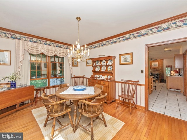 dining room with an inviting chandelier, crown molding, and light wood finished floors