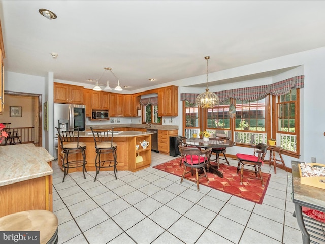 kitchen featuring a center island, light tile patterned floors, stainless steel appliances, decorative light fixtures, and an inviting chandelier