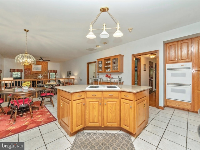 kitchen with light tile patterned floors, light countertops, a sink, double oven, and a notable chandelier